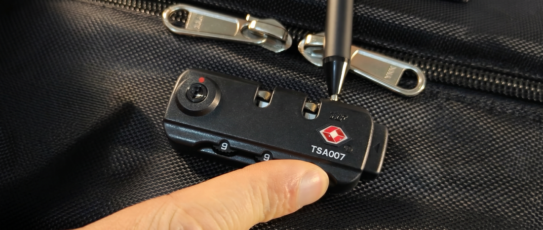 Close-up of changing the combination on a TSA007 luggage lock using the reset button on a rolling garment bag